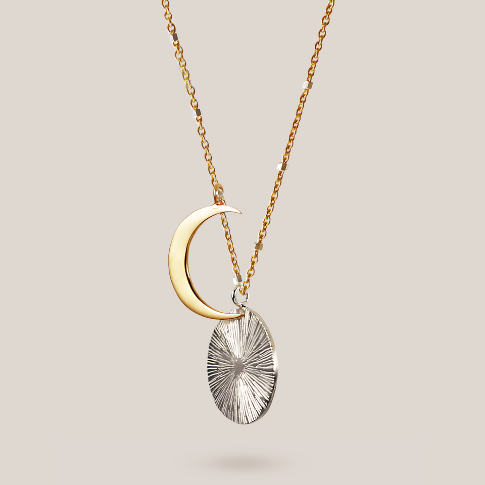 Gold crescent moon and silver textured pendant necklace on a light gray background